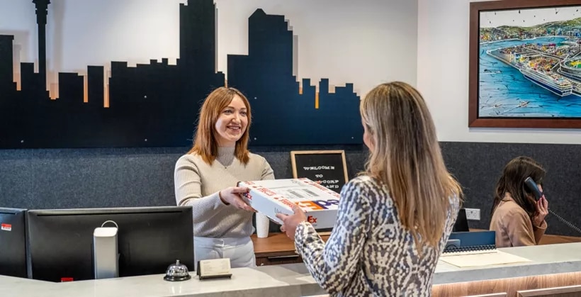 Dedicated receptionists helping a client in the modern coworking space of Servcorp 139 Quay Street, Auckland